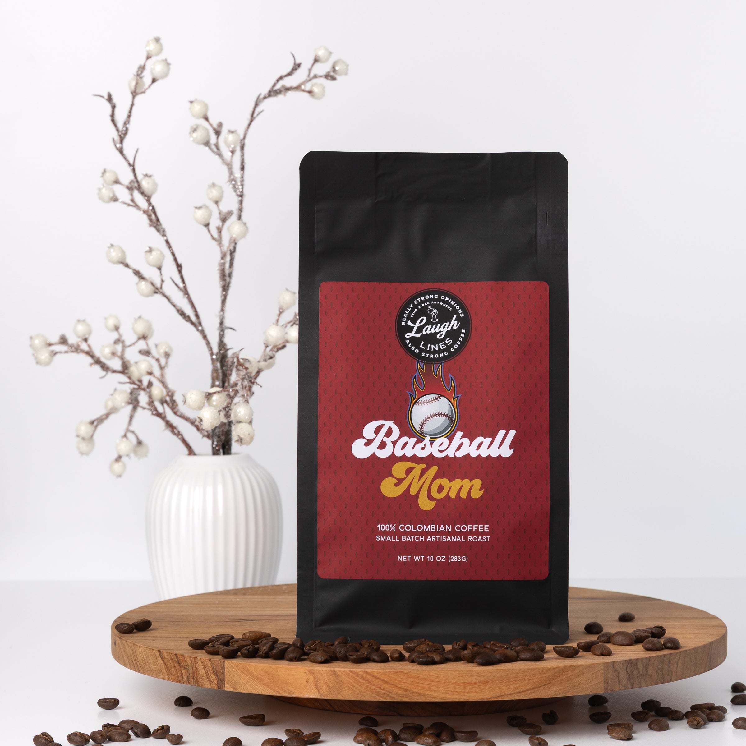 Coffee bag labeled 'Baseball Mom' on a wooden stand with coffee beans and decorative branches.