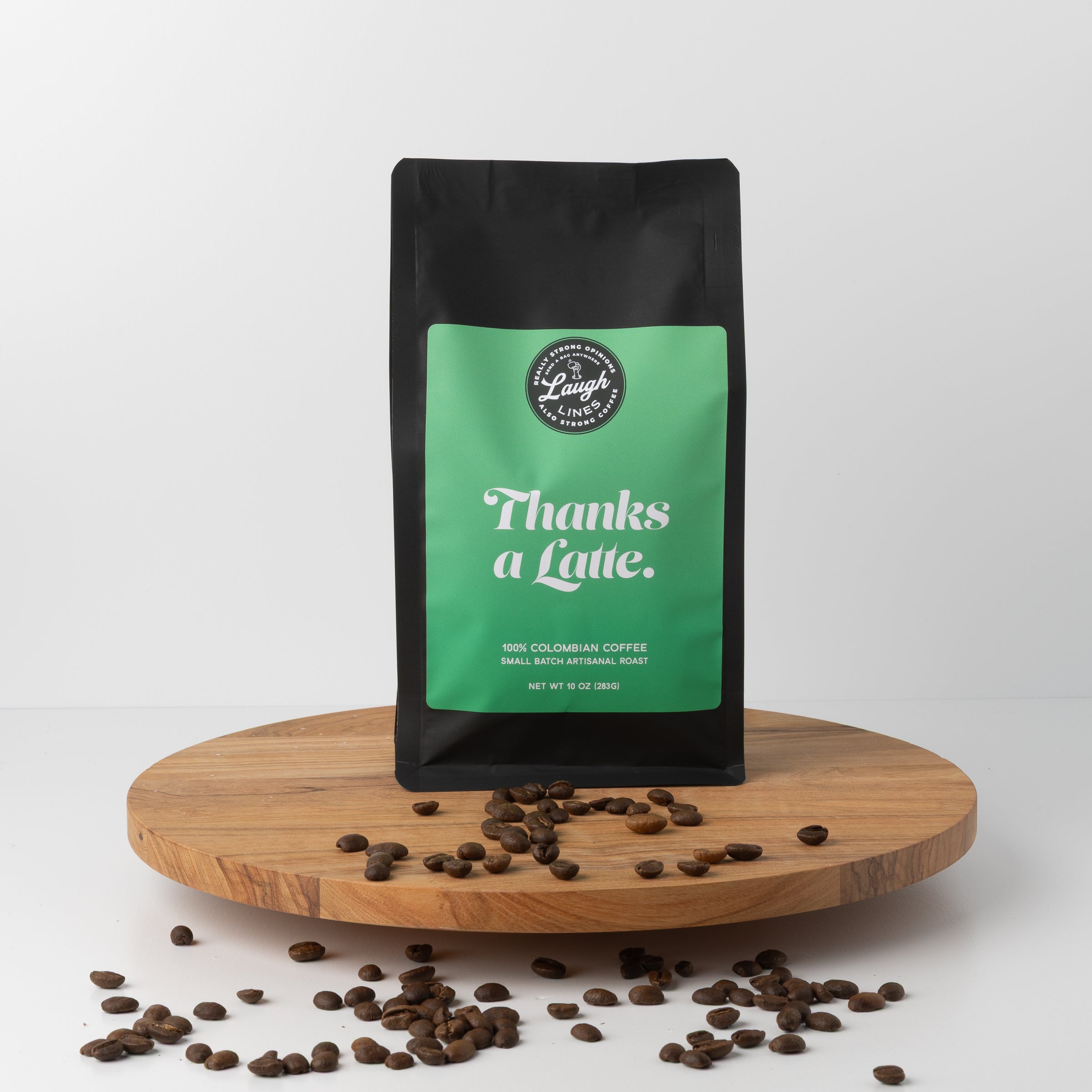 Coffee bag with 'Thanks a Latte' text on a wooden platform with scattered coffee beans.