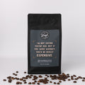Black coffee bag with humorous text that reads, "I'm not saying you're old, but if you were whiskey, you'd be really expensive," and coffee beans on a white background