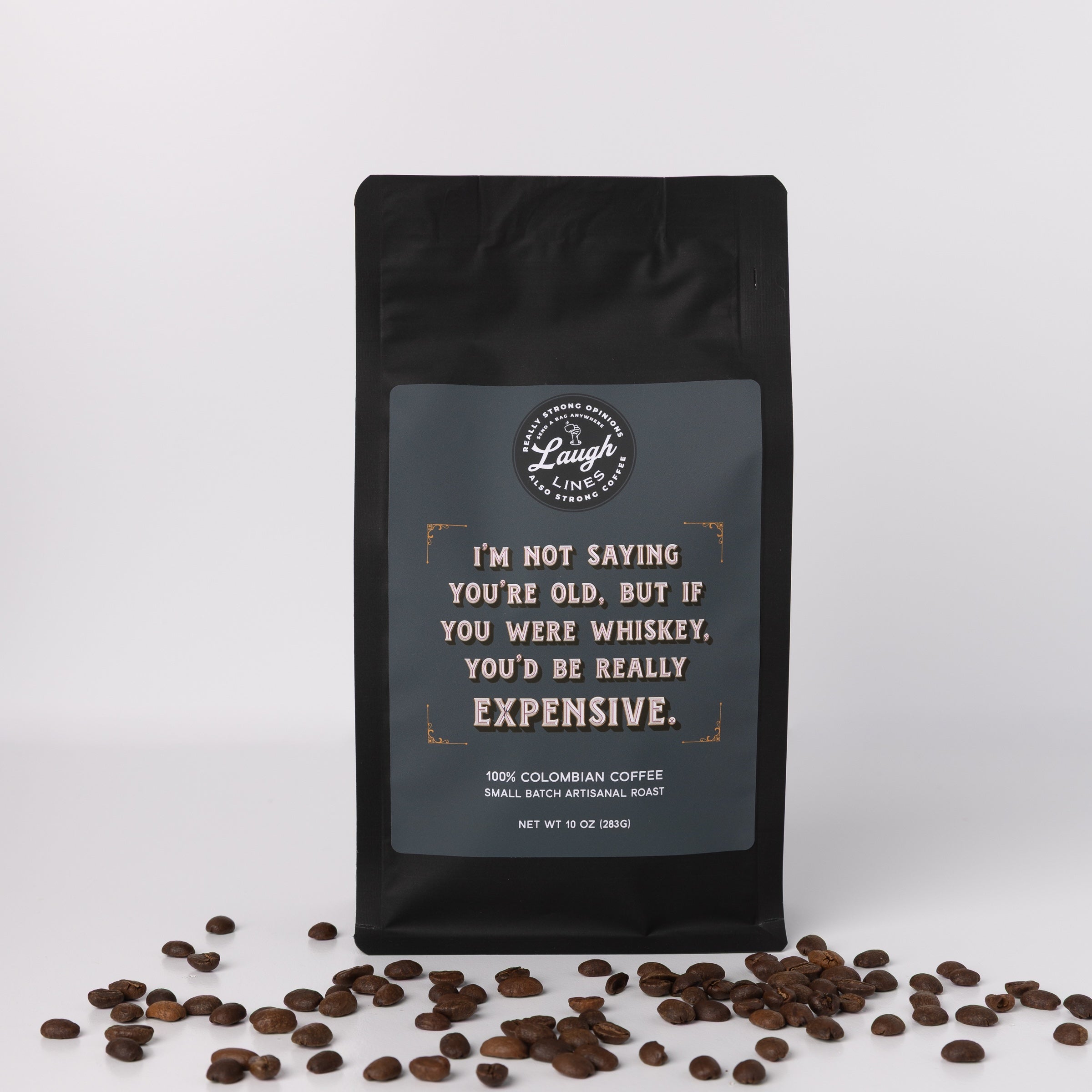 Black coffee bag with humorous text that reads, "I'm not saying you're old, but if you were whiskey, you'd be really expensive," and coffee beans on a white background