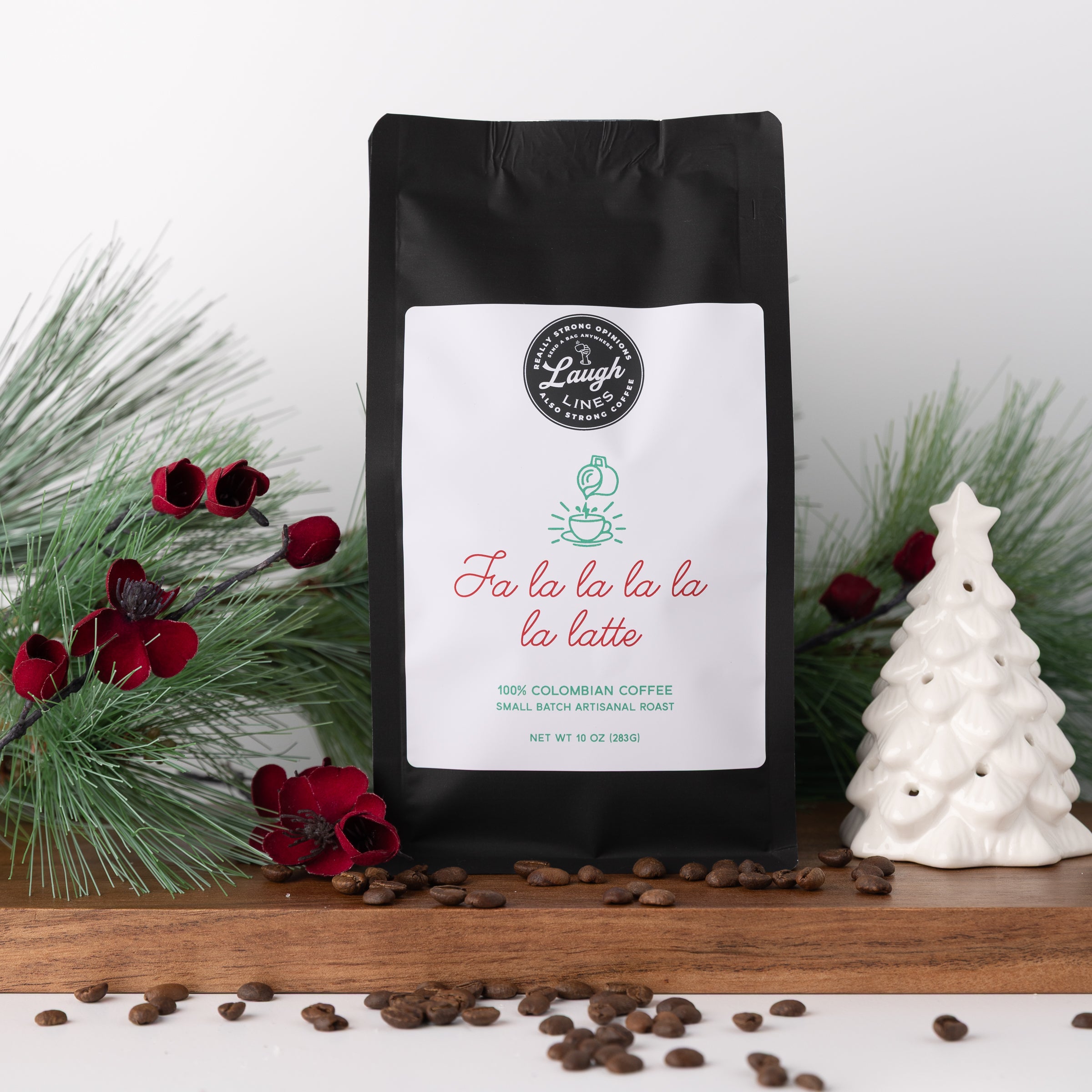Coffee bag with a festive label that reads 'Fa la la la la la latte' on a wooden surface with coffee beans and Christmas decorations.