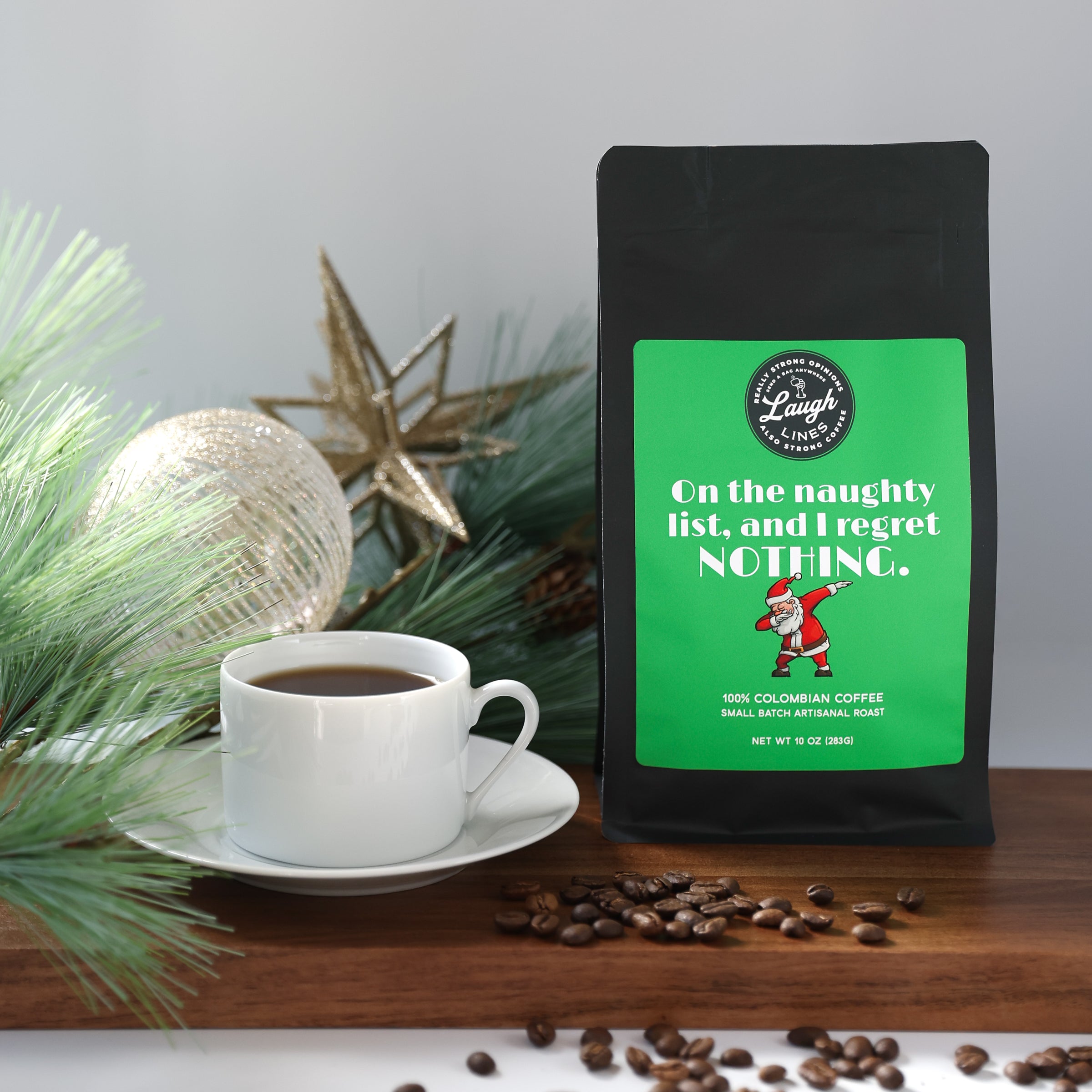 Coffee bag with humorous text that reads 'On the Naughty List, and I Regret Nothing' next to a cup of coffee and scattered beans on a wooden surface.