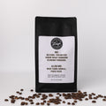 Coffee bag with humorous text that reads Me: Be Kind. You Never Know What Someone is going Through. Also Me: Nice Turn Signal F*ck Face on a white label and coffee beans on a white background