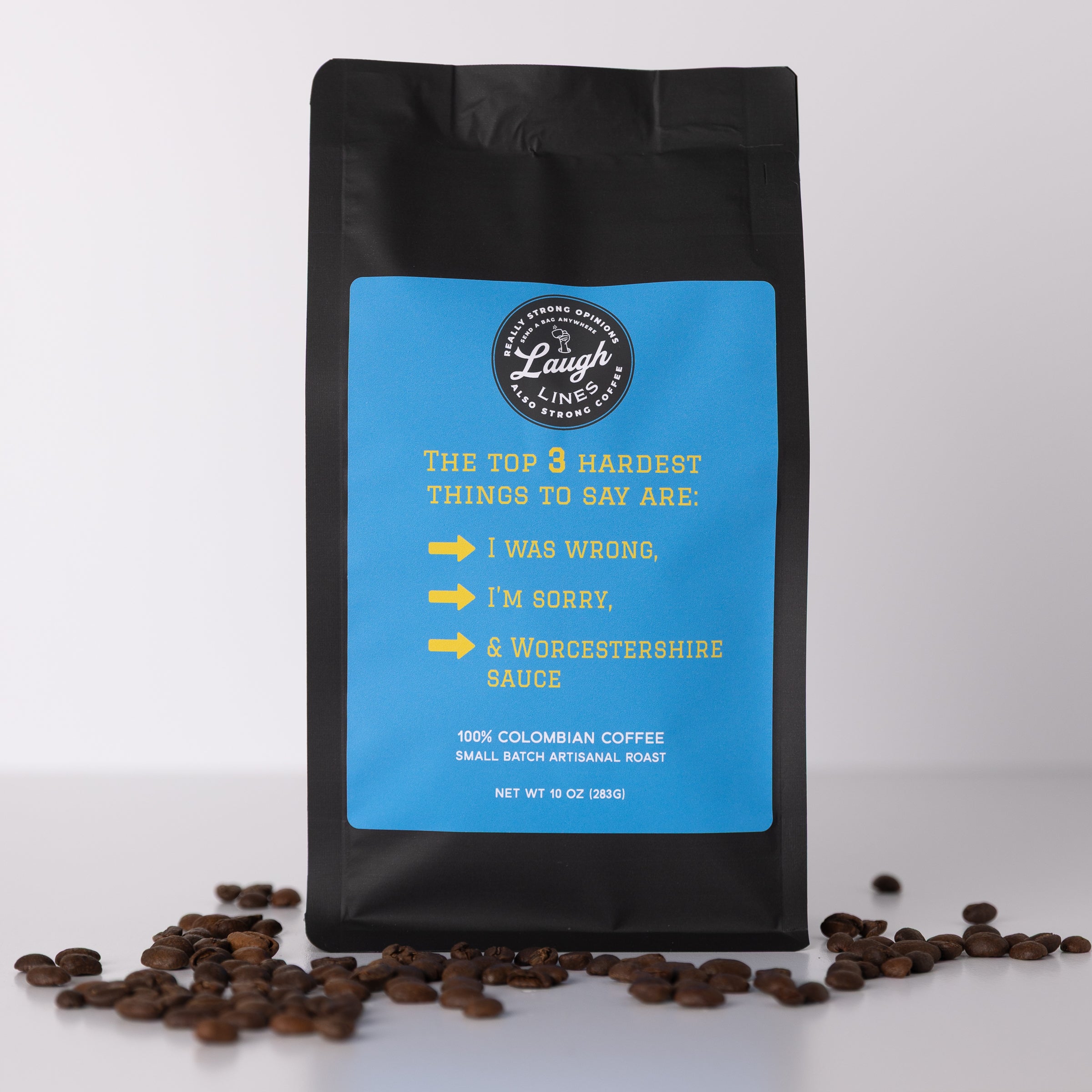 Coffee bag with blue label that says 'The Top 3 Hardest Things to Say Are: I was wrong. I'm sorry. & Worcestershire Sauce' and coffee beans on a white background