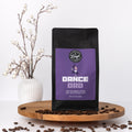 Coffee bag labeled 'Dance Dad' with coffee beans on a wooden surface and decorative elements.