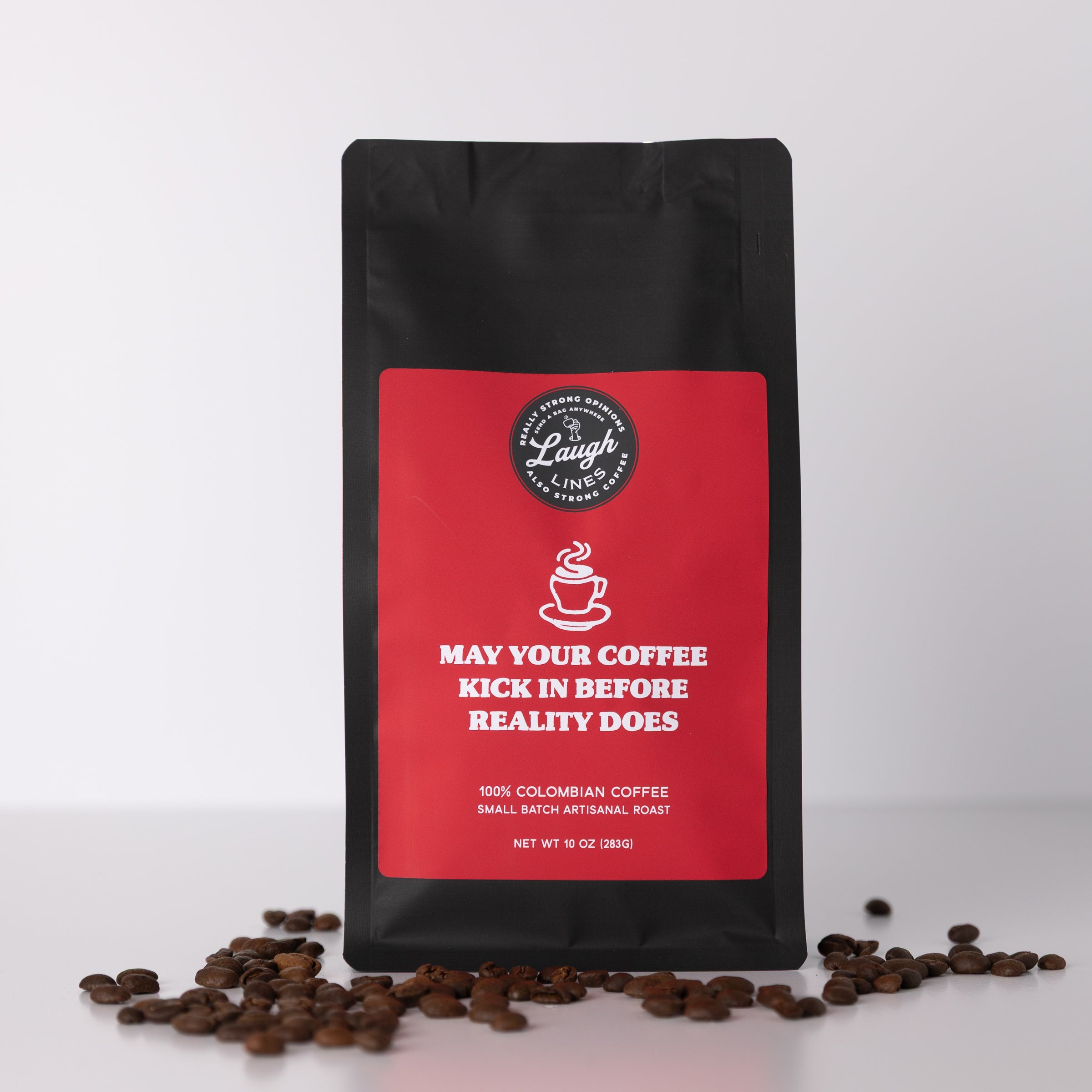 Black coffee bag with red label that reads 'May Your Coffee Kick in Before Reality Does' featuring coffee beans on a white background