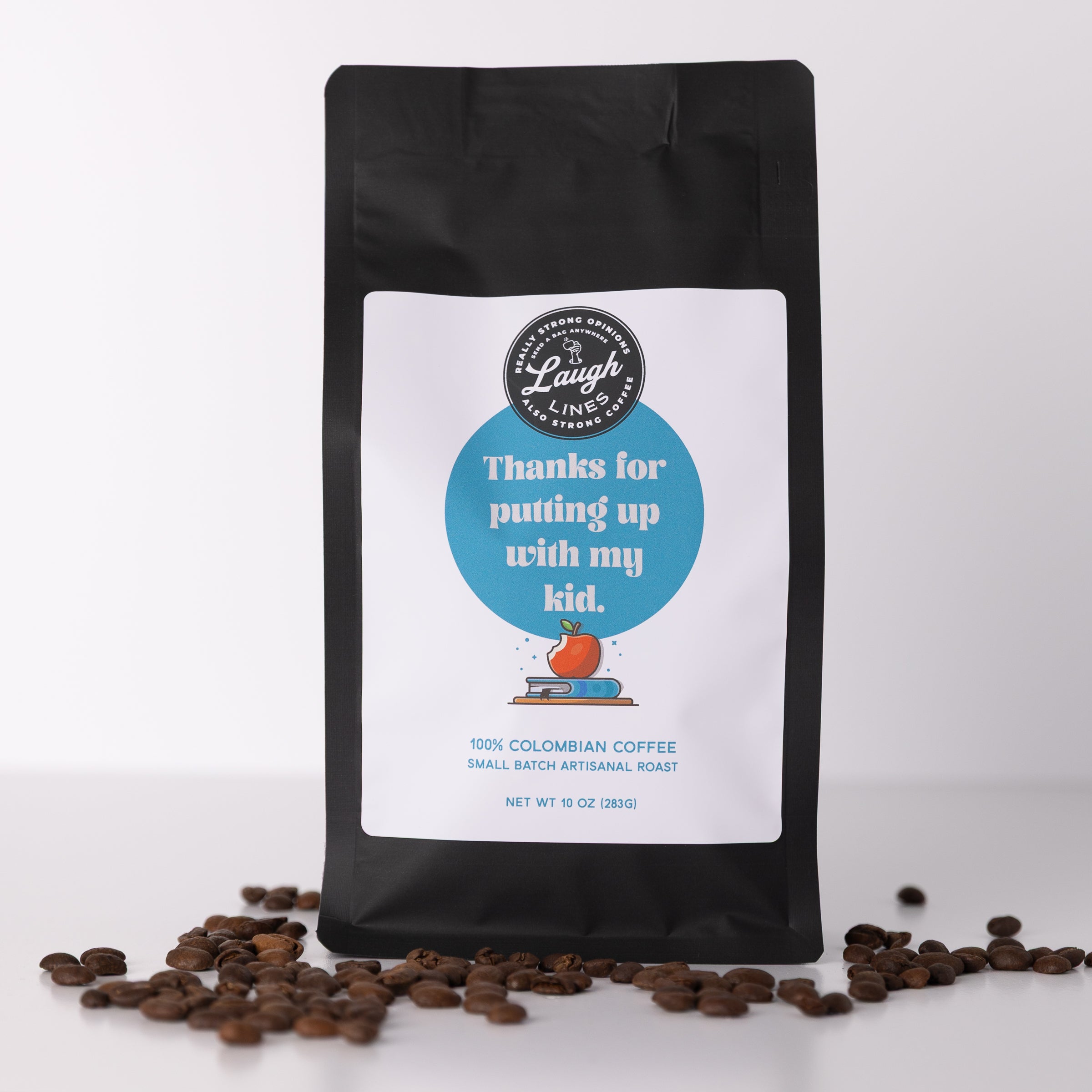 Coffee bag with a humorous label that reads 'Thank for putting up with my kid' and scattered coffee beans on a white background