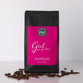 Coffee bag with pink label that reads "Girl, You've Got This!' and coffee beans on a white background